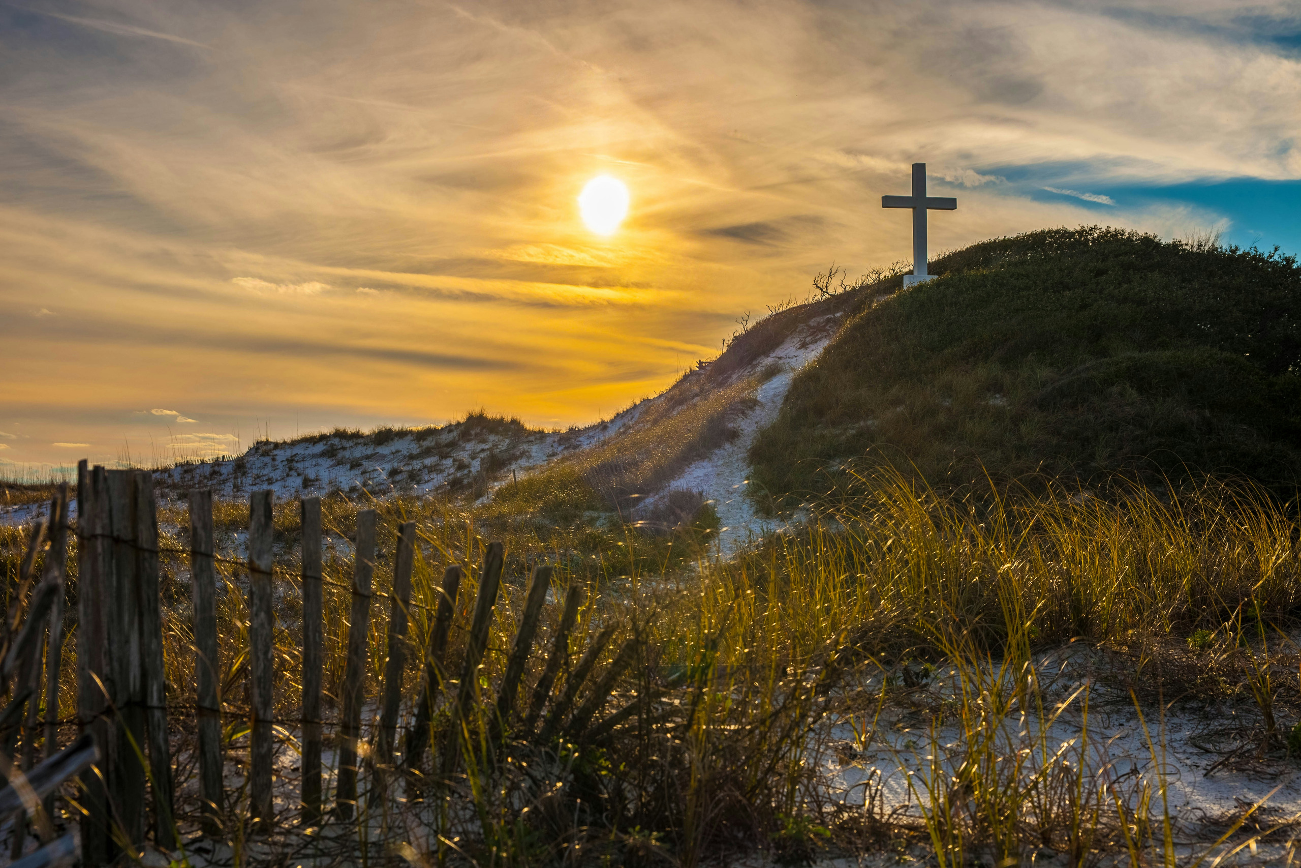 A cross on a hillside at sunrise